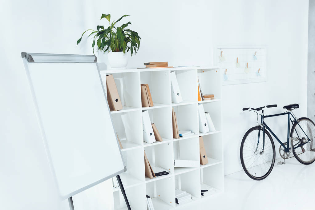 πινακάκι με ποδήλατο και ξύλινα ράφια στο άδειο γραφείο - Φωτογραφία, εικόνα