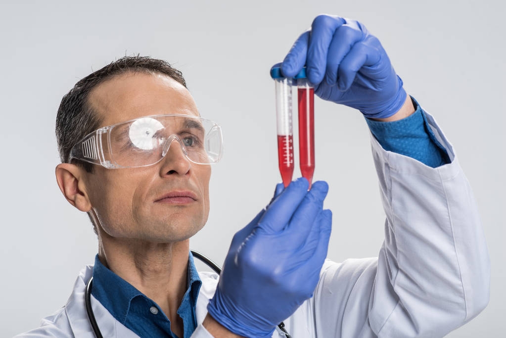 Elegante laboratorio masculino que examina la muestra de sangre
 - Foto, imagen