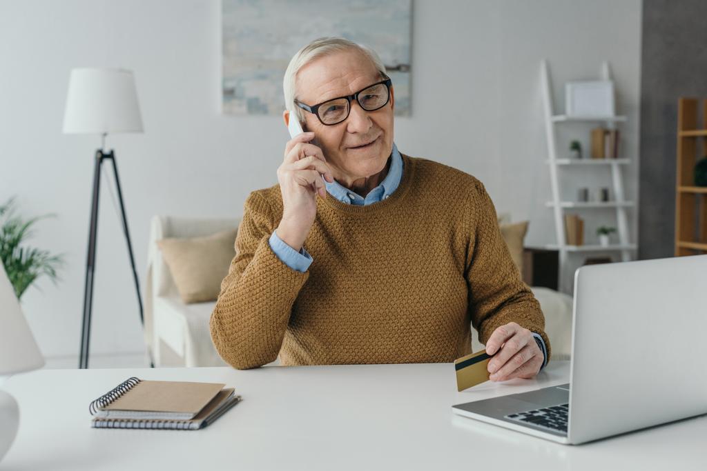 Yaşlı gülümseyen adam ofisinde çalışan ve telefon görüşmesi - Fotoğraf, Görsel