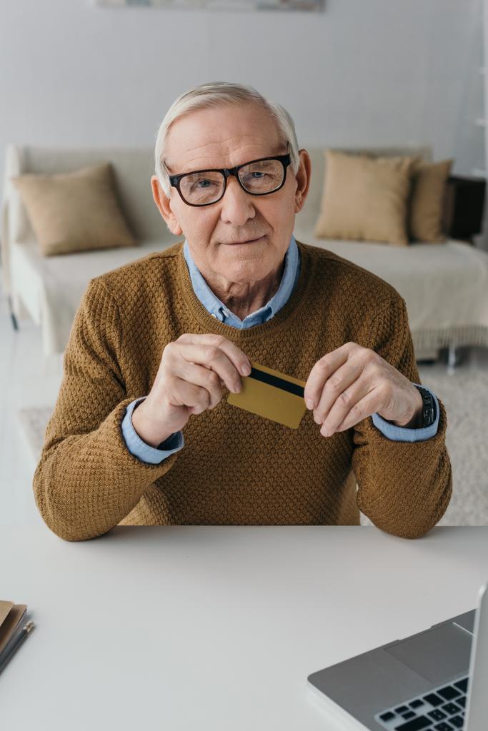 Senior homme confiant tenant la carte de crédit par ordinateur portable
 - Photo, image