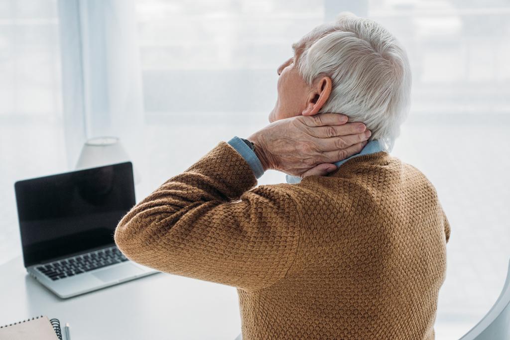 Ο πρεσβύτερος άνδρας εργάζεται σε γραφείο και υποφέρουν από πόνο στο λαιμό - Φωτογραφία, εικόνα