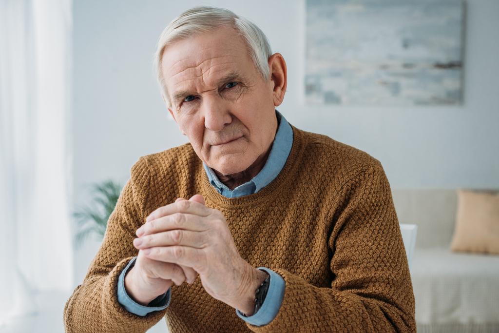 Vanhempi huomaavainen mies istuu pöydän ääressä valoisassa huoneessa
 - Valokuva, kuva