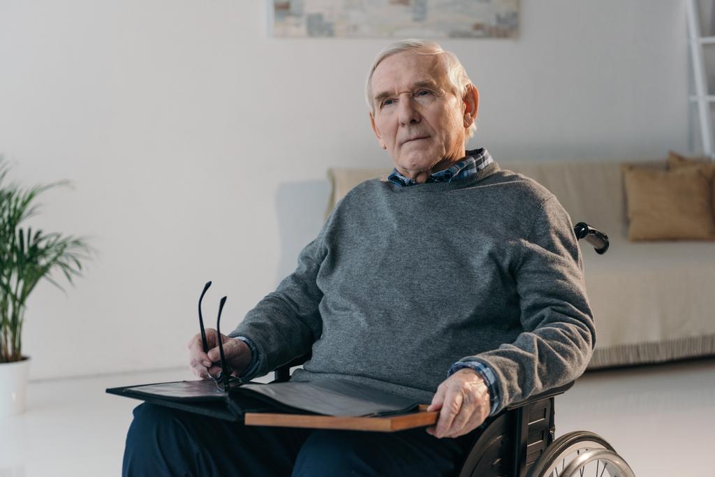 Homme âgé en fauteuil roulant tenant un vieil album photo
 - Photo, image