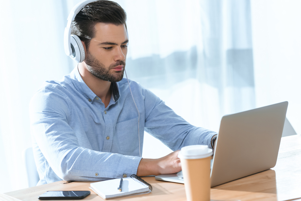 όμορφος επιχειρηματίας ακούει μουσική και να εργάζονται στο lap-top - Φωτογραφία, εικόνα