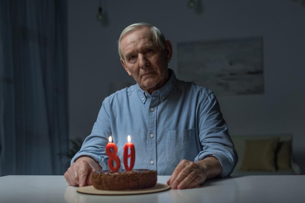Älterer einsamer Mann feiert 80. Geburtstag mit Kuchen und brennenden Kerzen - Foto, Bild