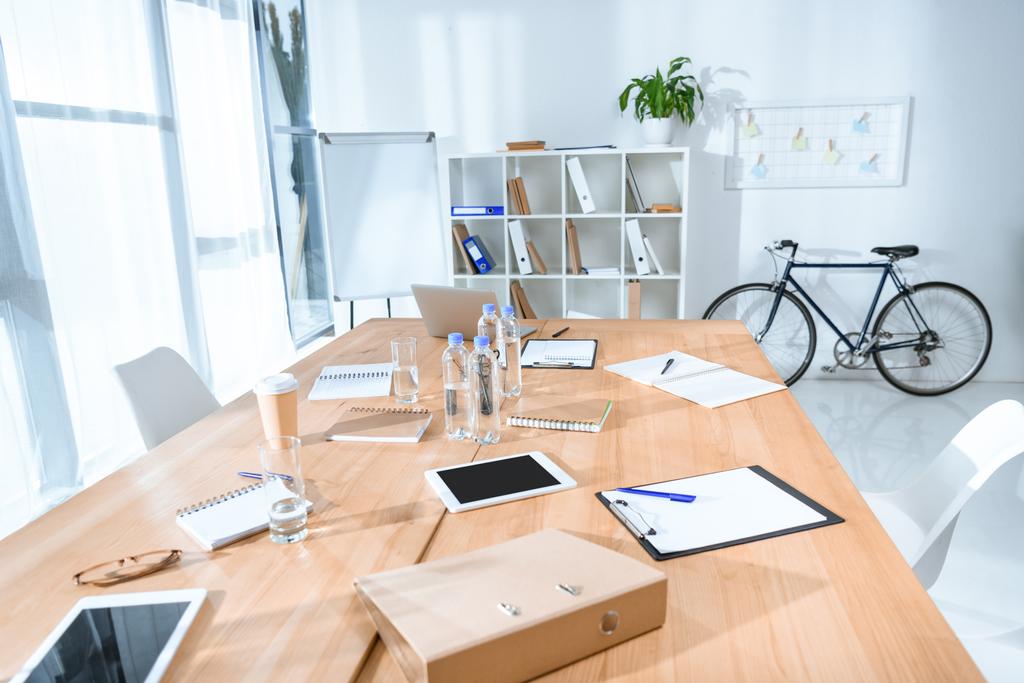 Blick auf leere Büroräume mit Tisch und Fahrrad gegen Wand  - Foto, Bild