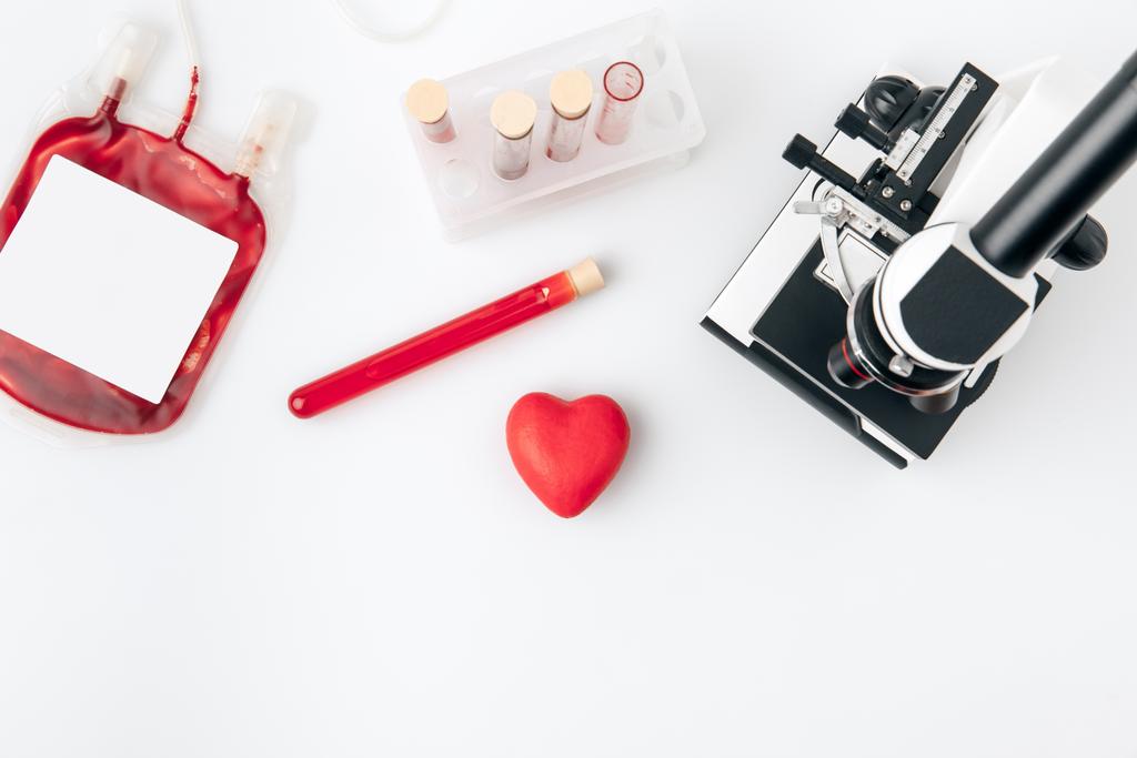 şişeleri kan ve beyaz arka plan üzerinde izole mikroskop ile karşı kırmızı kalp    - Fotoğraf, Görsel