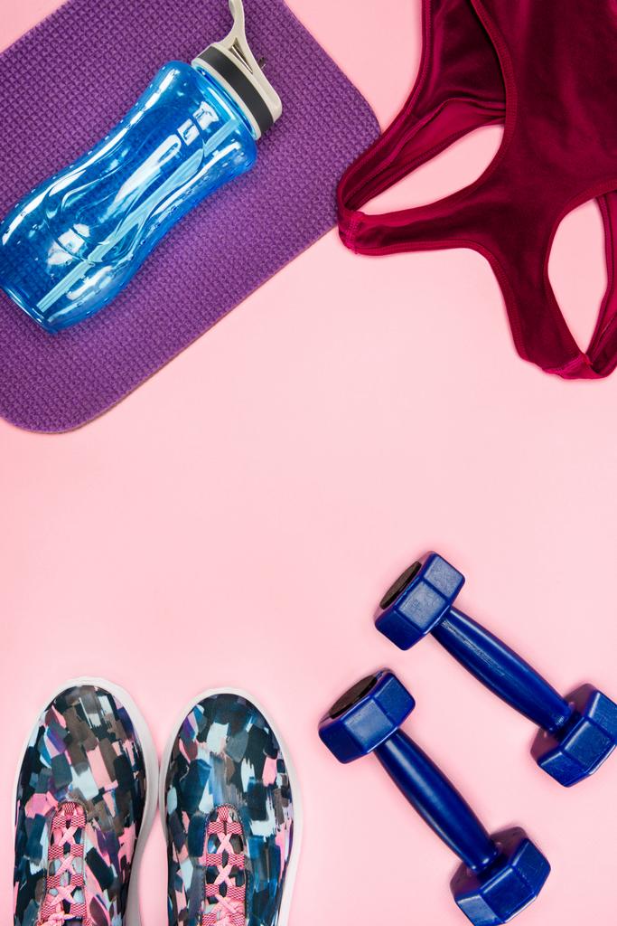 Спортивный инвентарь с обуви, гантели, спортивный топ и бутылка воды изолированы на розовый
 - Фото, изображение