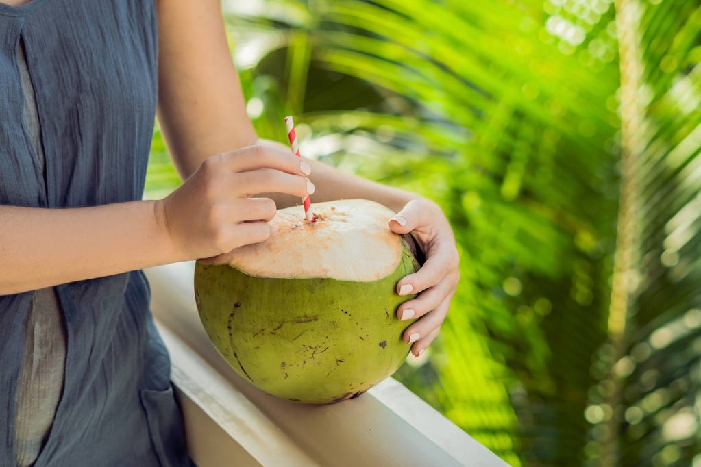 coco em belas mãos femininas em um fundo verde. Os benefícios do conceito de água de coco
. - Foto, Imagem