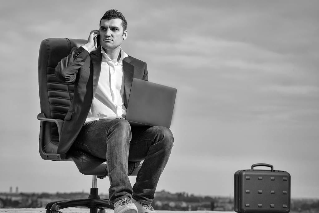 liikemies kannettavalla tietokoneella tuolilla ulkona
 - Valokuva, kuva