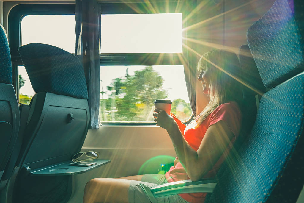Απολαμβάνοντας το ταξίδι. Νέοι όμορφη γυναίκα που ταξιδεύουν με το τρένο, καθισμένος κοντά στο παράθυρο και ποτό καφέ. - Φωτογραφία, εικόνα