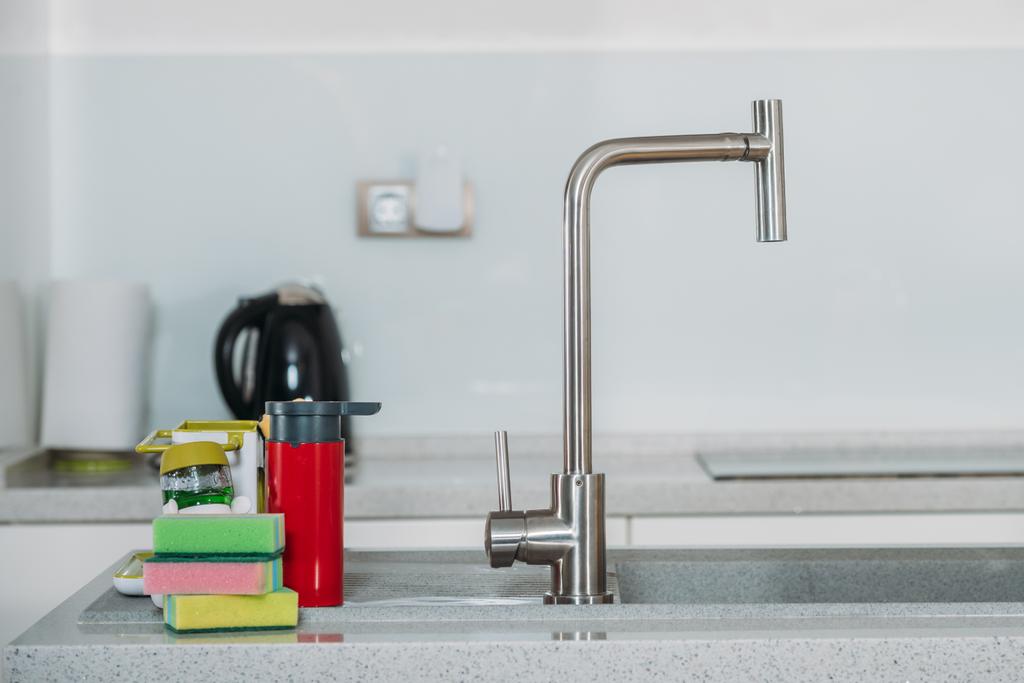 spugne per lavastoviglie vicino al rubinetto dell'acqua in cucina
 - Foto, immagini