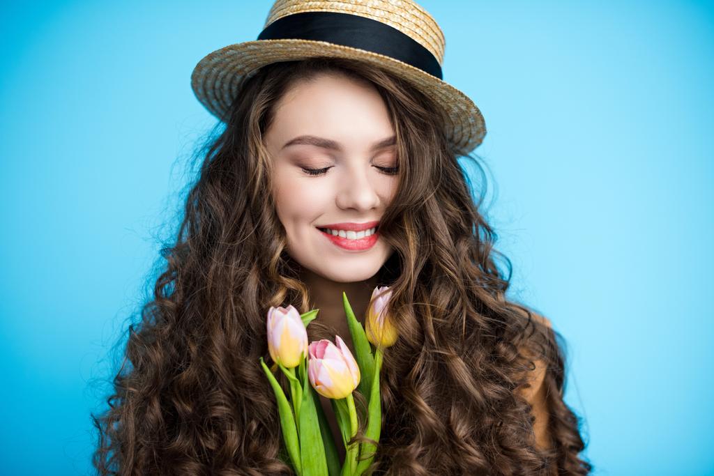 onnellinen nuori nainen pitkät kiharat hiukset kanootti hattu tilalla kauniita tulppaanit
 - Valokuva, kuva