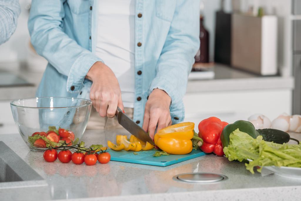 bijgesneden afbeelding van vrouw snijden van groenten voor salade - Foto, afbeelding