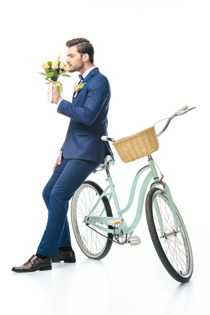 stylish groom with wedding bouquet leaning on retro bicycle isolated on white - Photo, Image
