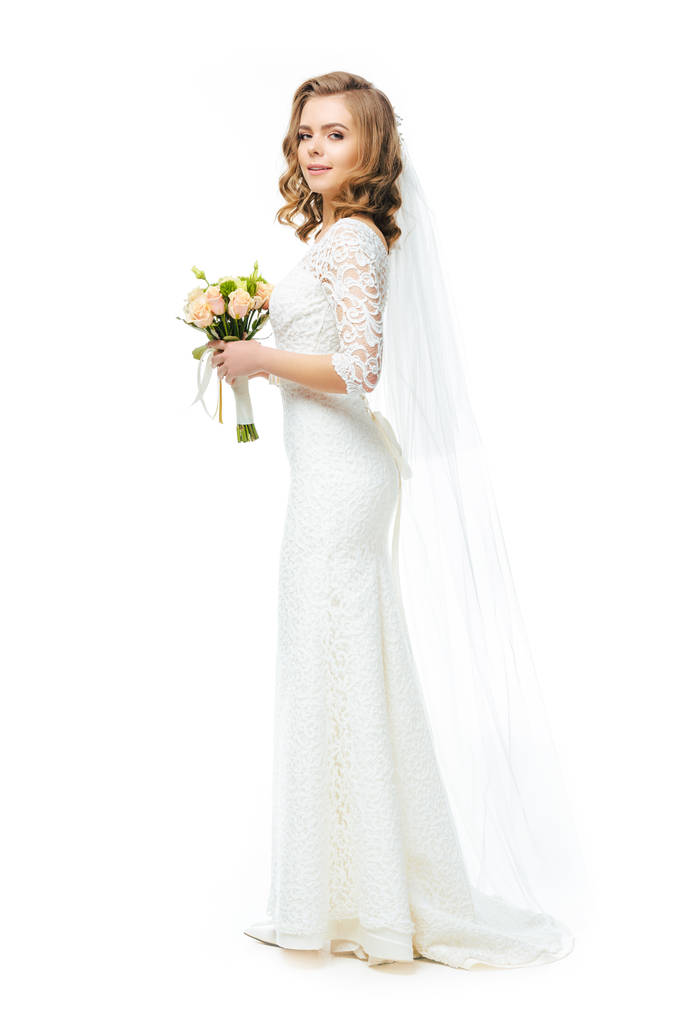 vista lateral de novia atractiva en vestido de novia y velo con ramo de flores aisladas en blanco
 - Foto, imagen