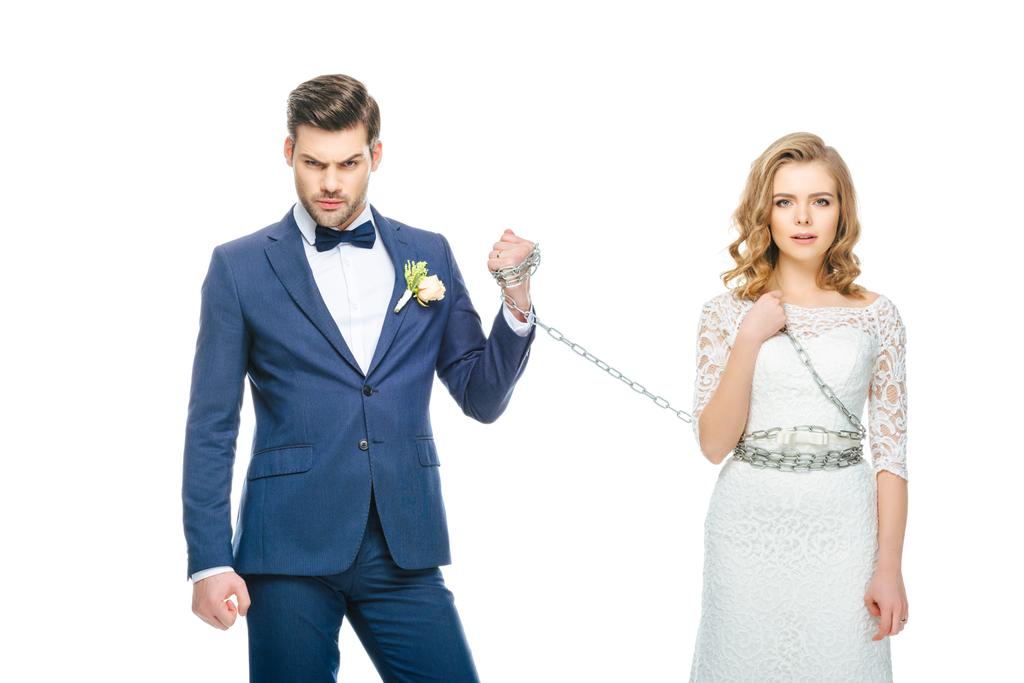 sposo tenendo scioccato giovane sposa sulla catena isolato su bianco
 - Foto, immagini