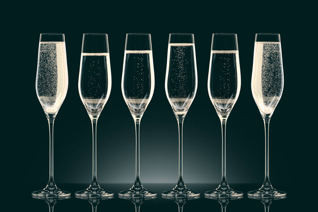 zes transparante glazen met verschillend niveau van champagne op zwart - Foto, afbeelding