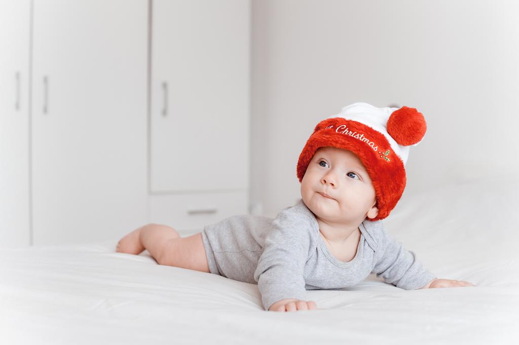portrait d'un petit enfant en chapeau de Père Noël couché sur le lit et regardant ailleurs
  - Photo, image