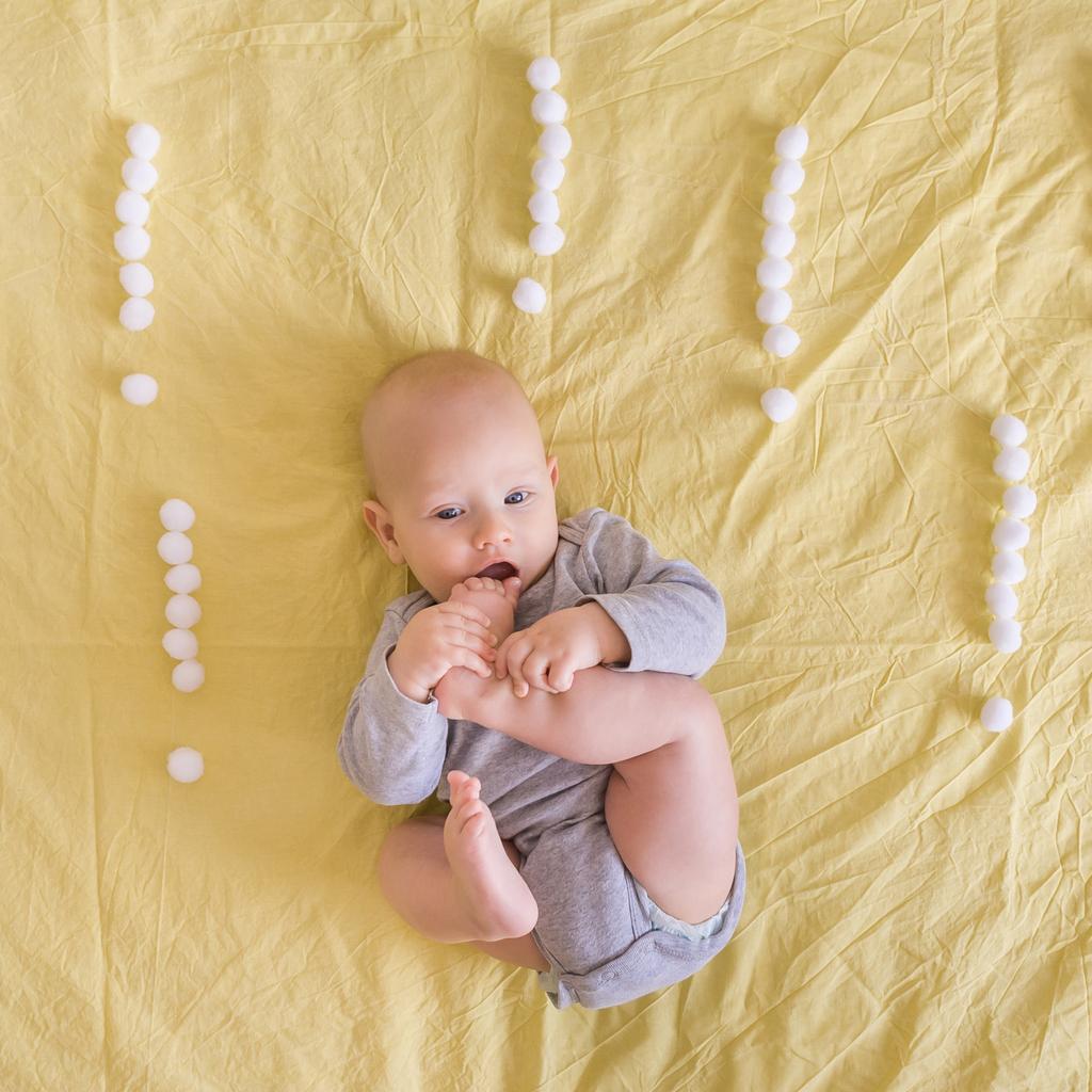 vue de dessus de mignon bébé couché entouré de points d'exclamation faits de boules de coton au lit
  - Photo, image