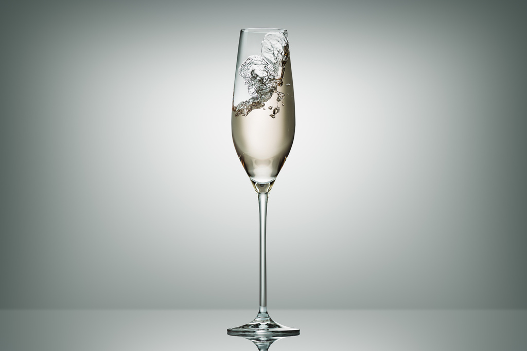 πιτσίλισμα σαμπάνια σε διαφανές γυαλί σε λευκό - Φωτογραφία, εικόνα