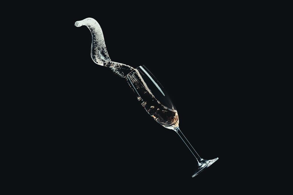 spilling champagne from falling glass isolated on black - Photo, Image
