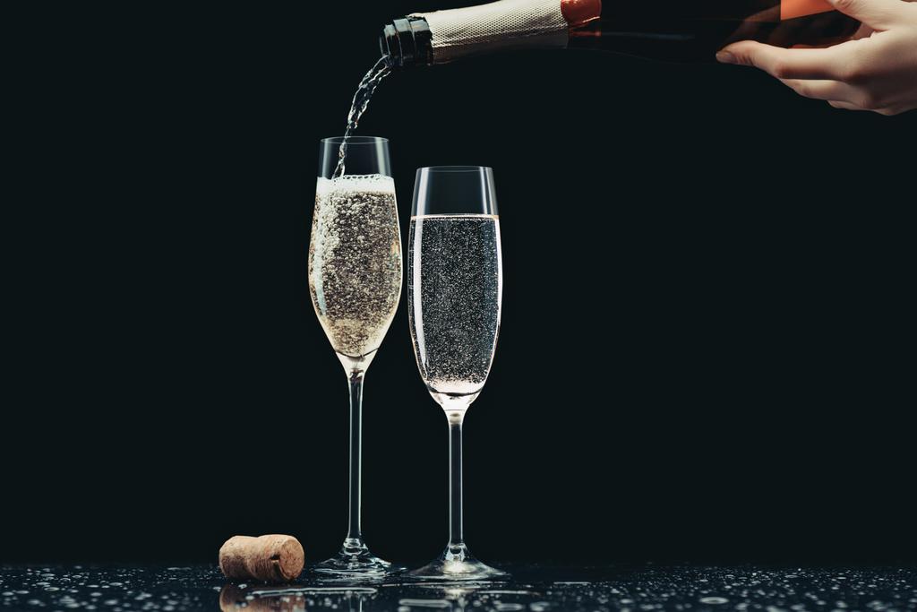 wykadrowanego obrazu kobieta strugach szampana z butelki do szklanek na czarny - Zdjęcie, obraz