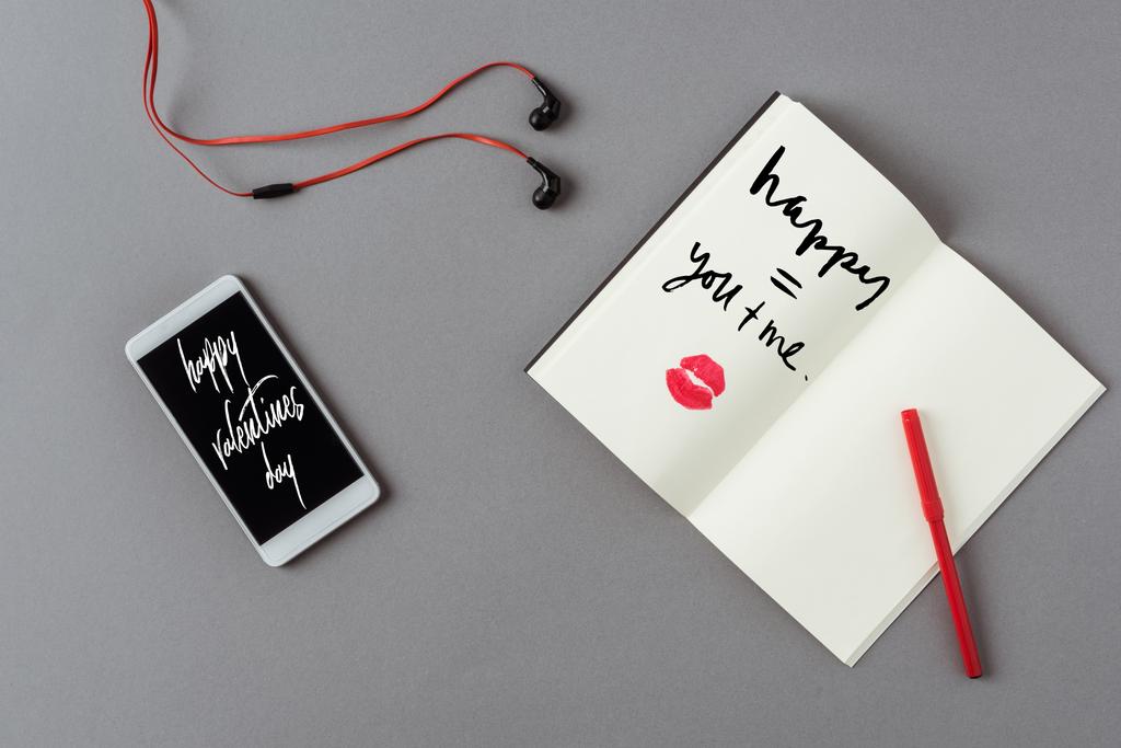 Nejlepší pohled na smartphone se slovy šťastné valentinky a notebook se rty tiskne na šedý povrch - Fotografie, Obrázek