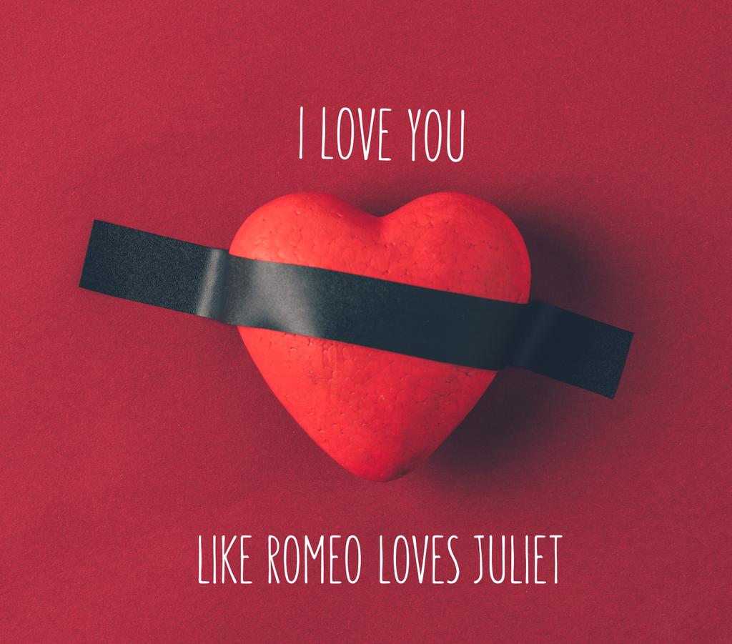 bovenaanzicht van rood hart onder isolerende tape met woorden die ik hou van je zoals Romeo houdt van Juliet op rood  - Foto, afbeelding