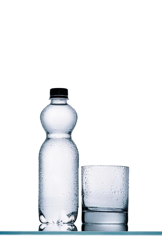 mokre pełne plastikowe butelki wody i pustą szklankę na białym tle - Zdjęcie, obraz