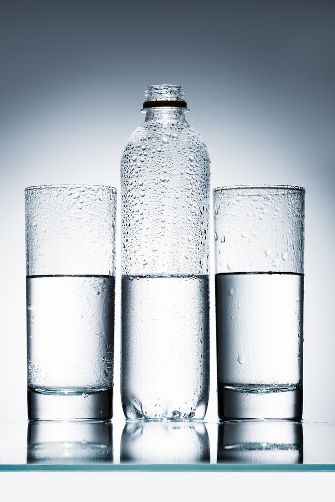 bouteille en plastique et verres d'eau propre en rangée sur une surface réfléchissante
 - Photo, image