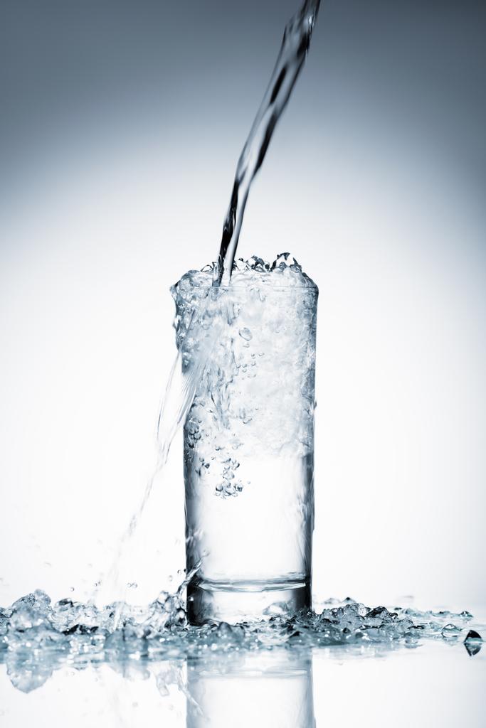 Close-up shot van water gieten in glas op wit  - Foto, afbeelding