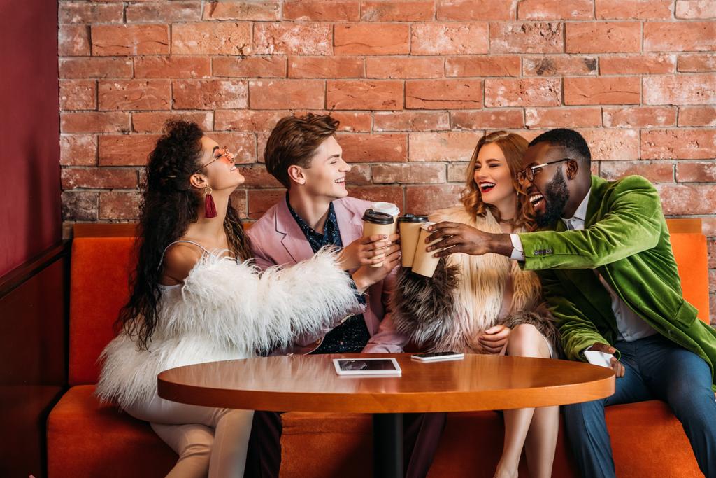 Улыбающиеся модные многонациональные молодые друзья пьют кофе из бумажных стаканчиков
 - Фото, изображение