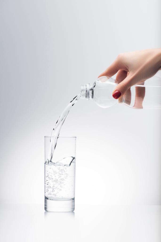 plan recadré de la femme versant de l'eau dans le verre de bouteille en plastique
 - Photo, image