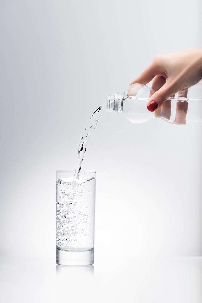 tiro recortado de la mujer vertiendo agua en el vidrio de la botella de plástico
 - Foto, Imagen