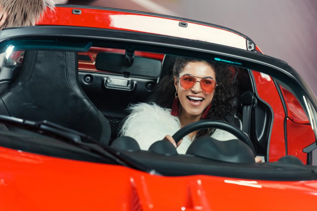 happy stylish young african american woman in fur coat driving luxury luxury car - Photo, Image