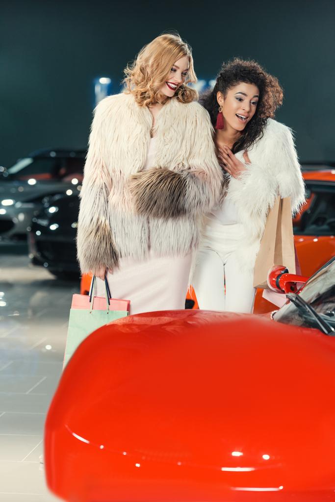 jeunes femmes en manteaux de fourrure regardant la voiture dans le showroom
 - Photo, image