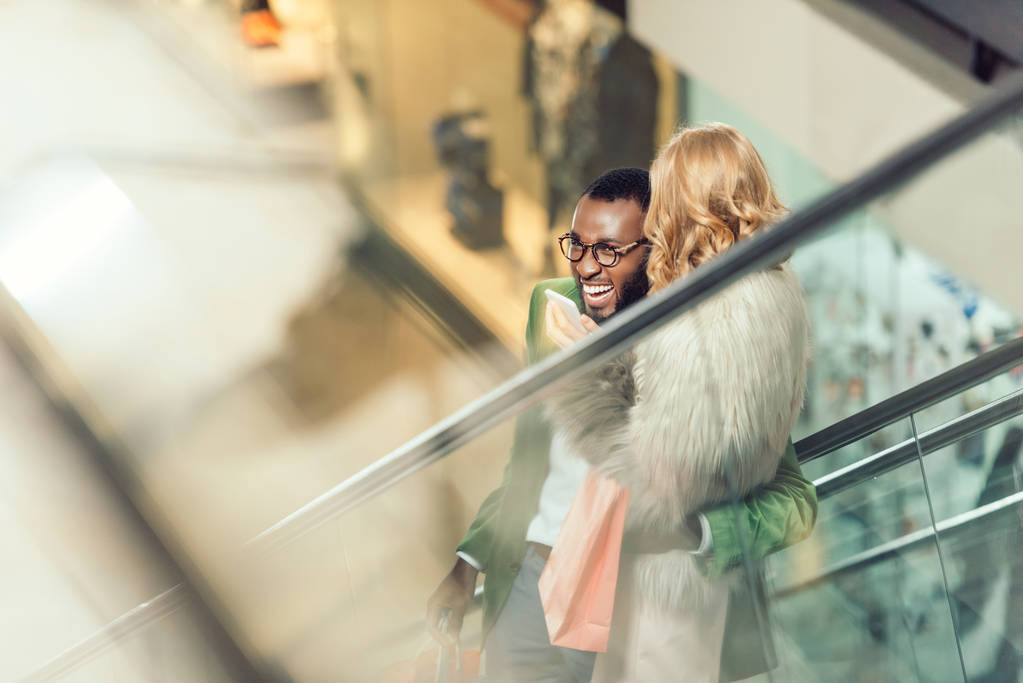 κομψό νεαρό ζευγάρι Καβάλα κυλιόμενες σκάλες και Αγκαλιάζοντας στο εμπορικό κέντρο - Φωτογραφία, εικόνα