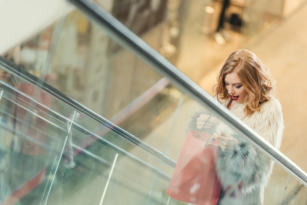 mujer sorprendida con bolsa de compras montar escaleras mecánicas
 - Foto, Imagen
