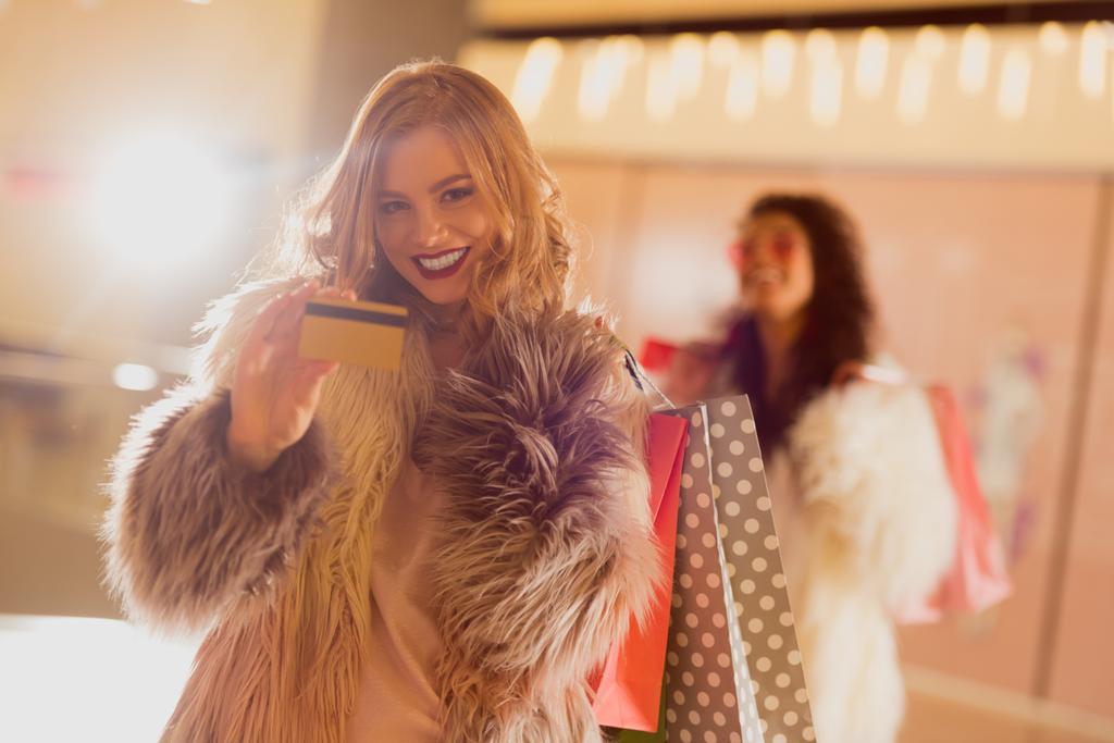 kürk ceket altın kredi kartıyla alışveriş üzerinde gülümseyen genç kadın - Fotoğraf, Görsel