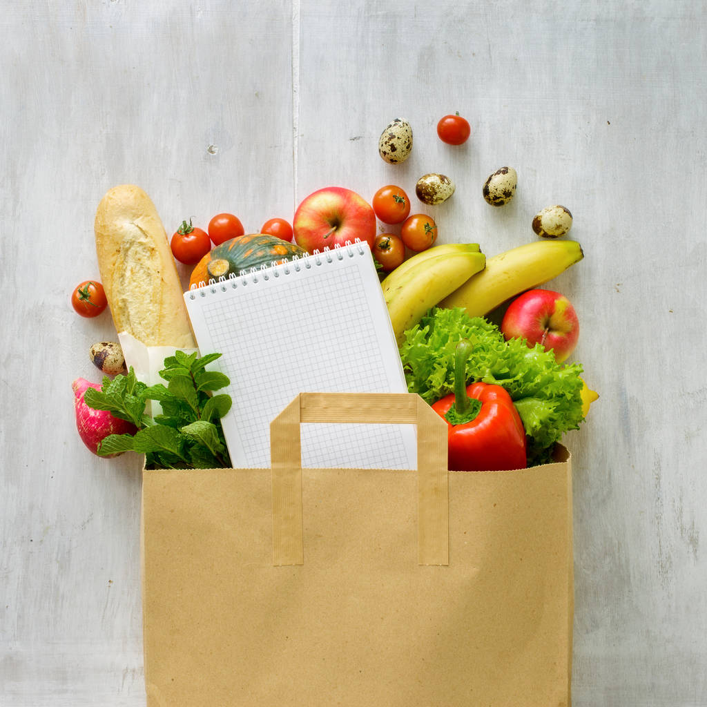 Paper bag of different health food and notebook white background - Photo, Image