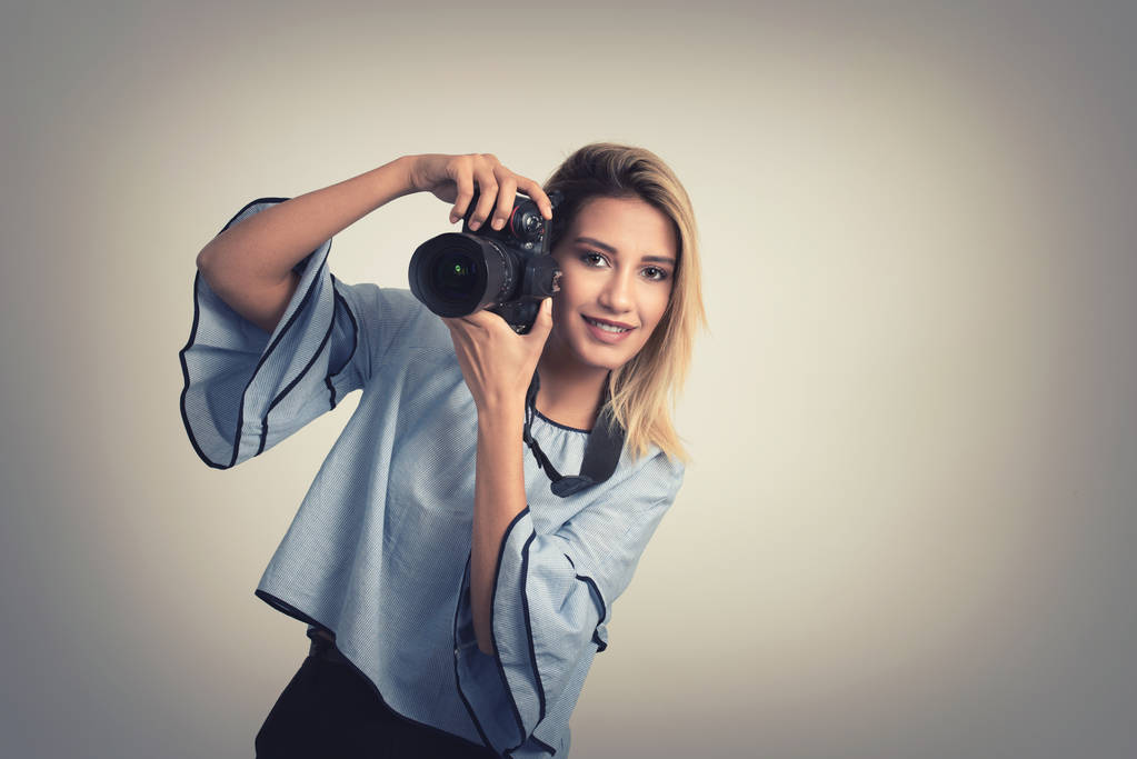 Vrolijke jonge vrouw foto maken op camera over grijze achtergrond - Foto, afbeelding