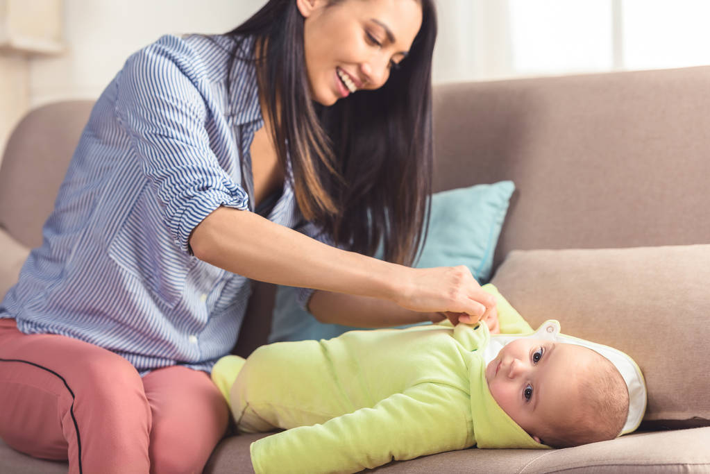 smiling mother dressing infant baby up at home - Photo, Image