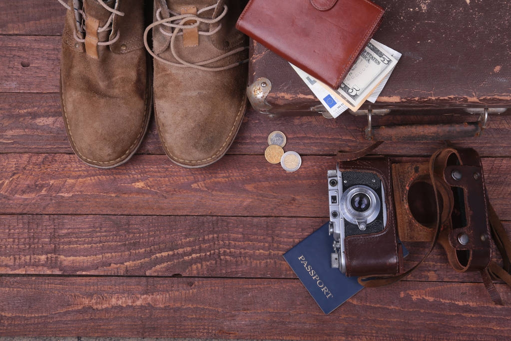 Concept de voyage avec valise Vintage, lunettes de soleil, vieil appareil photo, bottes en daim, étui pour l'argent et passeport sur sol en bois
. - Photo, image