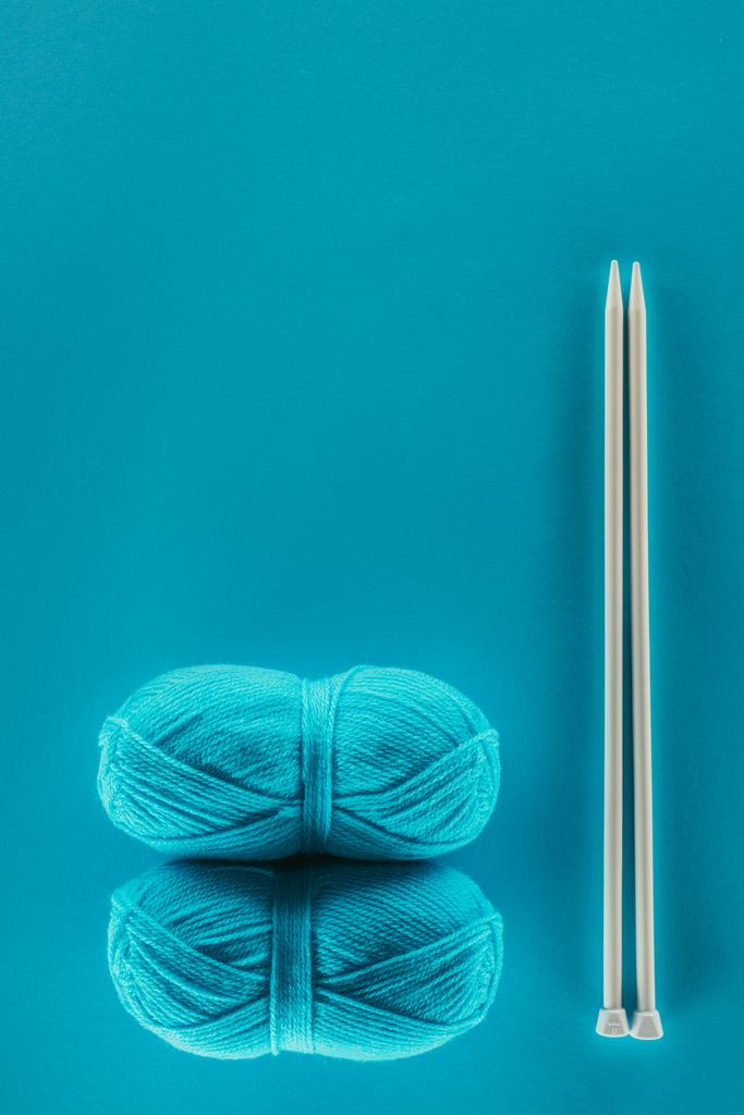 top view of blue knitting yarn balls with knitting needles, isolated on blue - Photo, Image