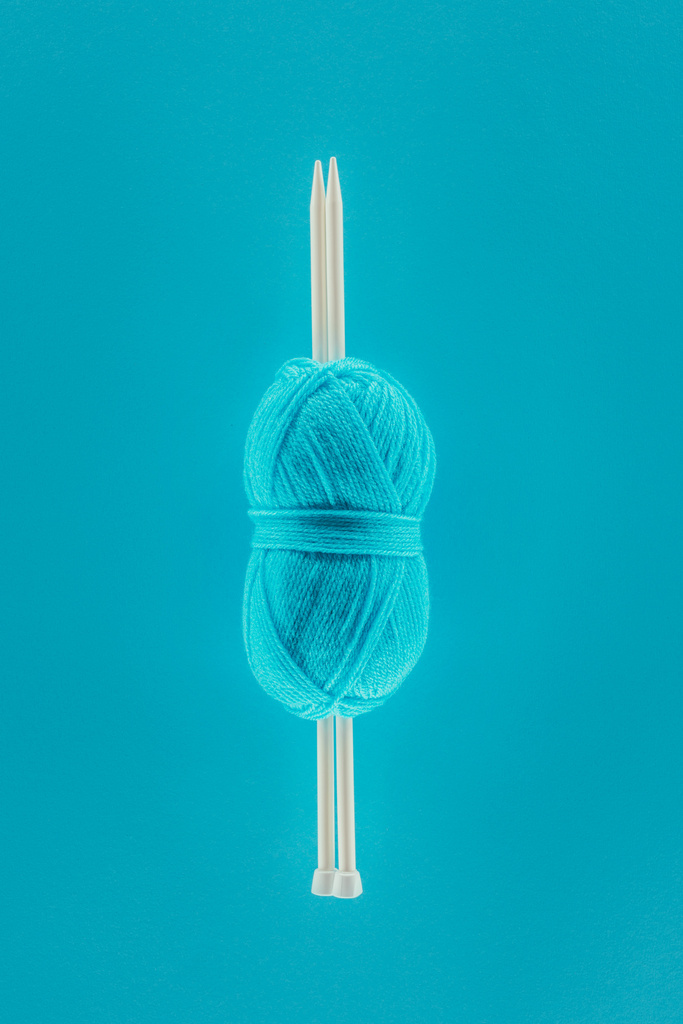 вид сверху на голубой вязальный нитевидный шар с вязальными спицами, изолированный на голубом
 - Фото, изображение