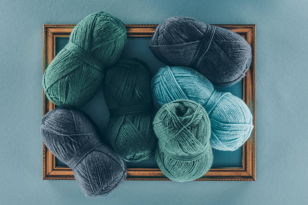 vista dall'alto di palline di lana lavorate a maglia blu e verde su telaio, isolate su blu
 - Foto, immagini