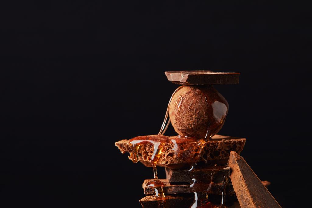 Close-up van regeling van truffel met karamel en chocolade bars geïsoleerd op zwart - Foto, afbeelding