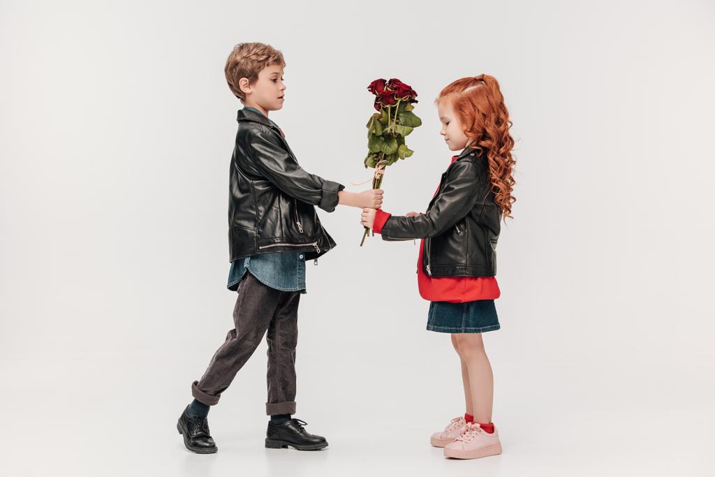 hermoso niño presentando rosas ramo a su novia aislado en gris
 - Foto, imagen