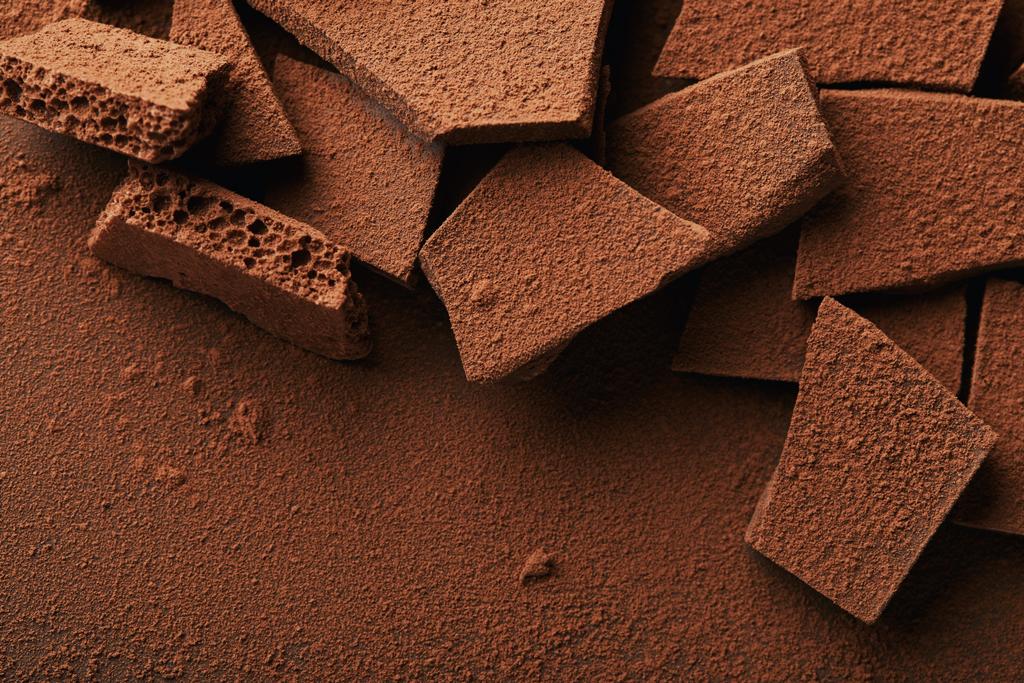 κοντινό πλάνο προβολής σωρού του Μπάρες σοκολάτας σε σκόνη κακάο - Φωτογραφία, εικόνα